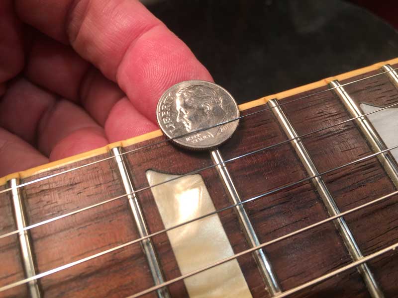 Using a dime to check the string height on the treble side of a Les Paul