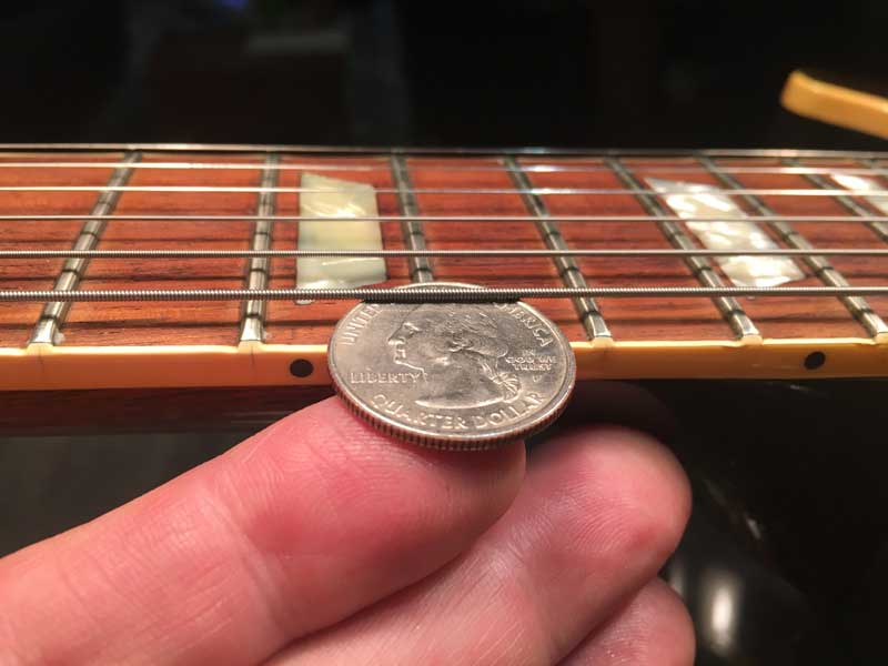 Using a quarter to check the string height on the bass side of a Les Paul